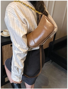 Detailansicht der braunen Hobo-Tasche mit goldener Kette über der Schulter getragen