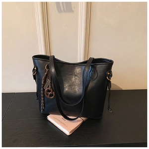 Close-up of black leather tote bag with embossed brand logo and gold hardware rings