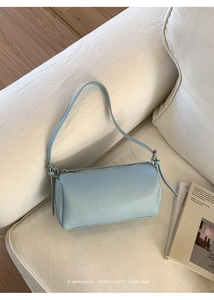 Detail of light blue cylinder crossbody bag showing fine lychee grain leather texture