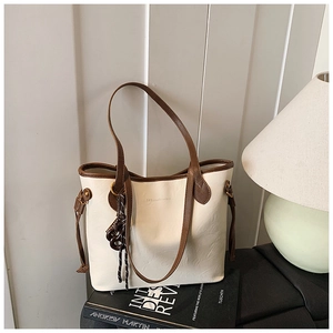 Detail of cream tote bag with dark brown straps and embossed logo in a lifestyle setting