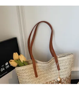 Close-up of brown leather strap and woven straw texture on a large beach tote bag