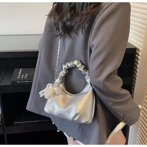 Détail du sac demi-lune argenté avec poignée froncée et breloque en perles et dentelle