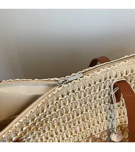 Detail of high-quality silver zipper closure on a woven straw tote bag with brown leather