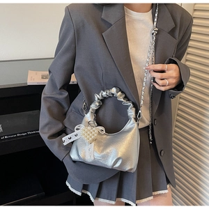 Détail du sac à main argenté avec breloque cœur en perle et décoration nœud en dentelle