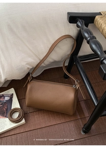 Detail of a brown lychee pattern leather barrel bag with silver zipper and strap