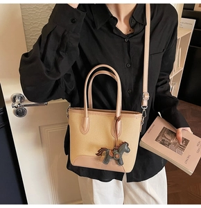 Detalle de bolso saco de lona y cuero rosa con un colgante de caballo decorativo