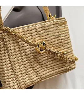 Detailed view of beige woven texture with gold chain strap and metal ball buckle