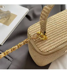 Close-up of beige woven texture and luxury gold chain hardware on a small box bag