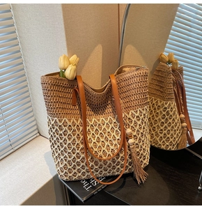 Macro detail of dual-color woven tote bag with leather handles and tassel charm