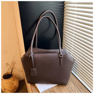 Close-up of brown pebbled leather tote bag showing rich texture and decorative tag