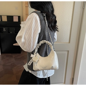 Détail du sac demi-lune plissé blanc avec breloque cœur perle et chaîne argentée