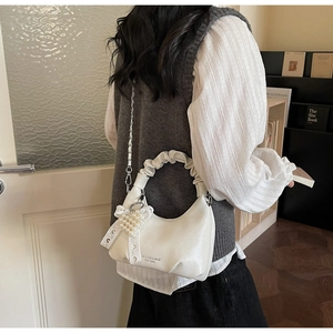 Détail d'un sac blanc à poignée plissée avec breloque perle et nœud en dentelle élégant