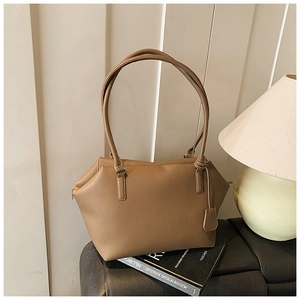 Detail of khaki tote bag showing pebble leather texture and brand tag in home setting