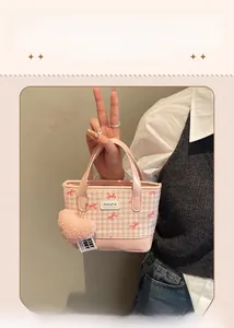 Pink checkered bucket bag featuring a red bow pattern and soft heart pendant detail