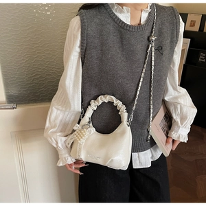 Détail d'un sac à main blanc crème avec breloque perle et poignée plissée style nuage