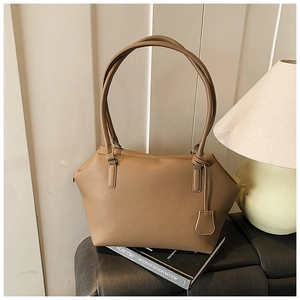 Brown litchi grain tote bag detail featuring shoulder strap and side decorative pendant