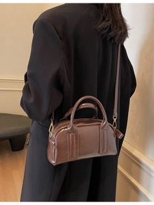 Borsa Boston vintage in pelle marrone con dettagli dorati indossata a spalla da modella