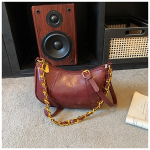 Nahaufnahme einer burgunderroten Vintage-Kette Handtasche mit glänzendem Leder und Gold