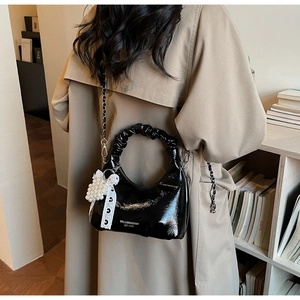 Détail du sac en cuir verni noir avec poignée plissée nuage et breloque perle et dentelle
