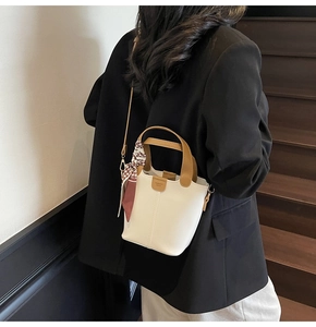 Detail of white mini bucket bag with fashion label and retro houndstooth silk scarf handle