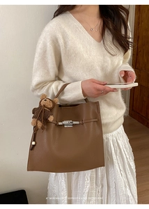 Detail of vintage brown textured leather handbag with silver lock and plush bear charm