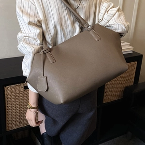 Detail of minimalist brown leather tote bag showing rich lychee texture and sturdy straps