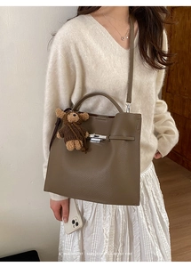 Detail of dark brown pebble leather handbag with silver clasp and teddy bear charm accessory