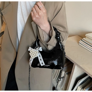 Détail du sac bandoulière en cuir verni noir avec nœud en perles et chaîne argent