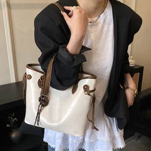 Detail of cream tote bag with brown leather handles and side drawstring on model