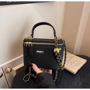 Detail of black woven texture mini box bag with golden ball adjustable chain strap