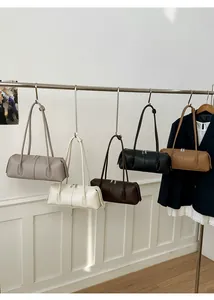 Detail view of colorful minimalist cylindrical leather bags hanging on metal hooks