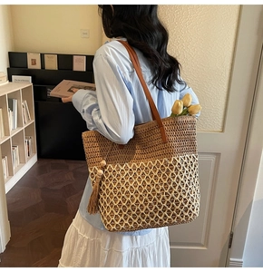 Detail of woven straw tote bag featuring leather handles and wood bead tassel charm
