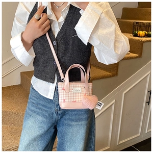 Détail du sac à main à carreaux roses avec pendentif cœur et bandoulière réglable