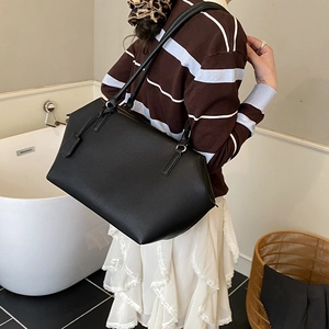 Detailed view of black lychee grain leather tote bag with long double shoulder straps