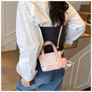 Pink plaid bucket bag with heart charm shown in a stylish lifestyle scene with a model