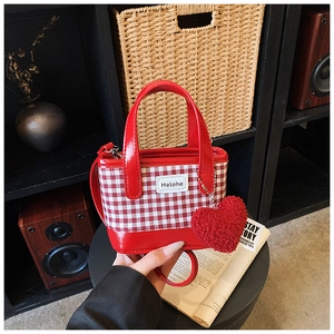 Detail of red and white checkered mini bucket bag with glossy base and heart pendant