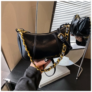 Detail der glänzenden schwarzen Mondtasche mit Goldkette und vertikalen Nähten im Spiegel