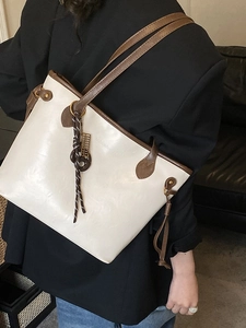 Chic cream tote bag with dark brown straps and decorative scarf on black blazer