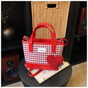 Detail of red and white checkered bucket bag with heart pendant and leather strap