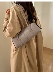 Close-up of a lilac pebbled leather shoulder bag worn with a beige trench coat