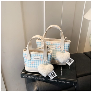Close-up of blue plaid bucket bags featuring pink bows and plush heart charms