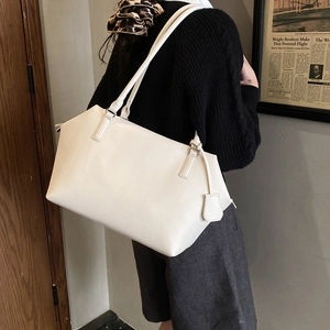 Detailed view of white minimalist tote bag with pebble leather texture and shoulder straps