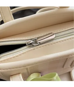 Detail of silver smooth metal zipper and premium cream white leather on bucket bag