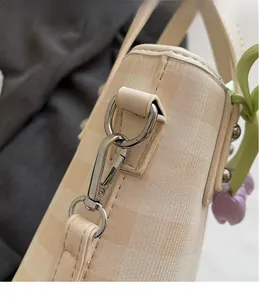 Detail of silver swivel hook on plaid fabric bag with purple tulip charm accessory
