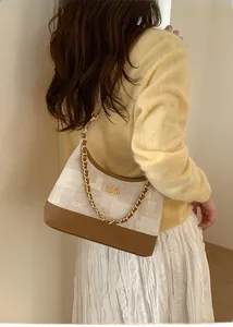 Détail du tissu à carreaux beige et cuir brun avec bandoulière chaîne dorée