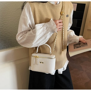 Detailed view of white textured box bag with gold chain and metal hardware on model
