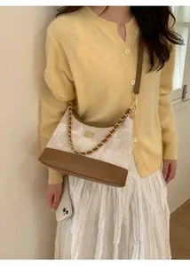 Détail du sac vintage en cuir marron et tissu blanc avec sa chaîne dorée élégante