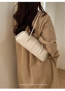 Close-up of cream minimalist shoulder bag with vertical stitching and textured leather