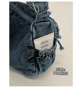 Detail of denim crossbody bag side pocket with elastic band and silver metal buckle
