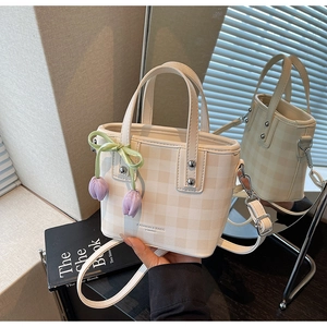 Détail du sac seau à carreaux avec pendentif tulipe et nœud en ruban vert élégant